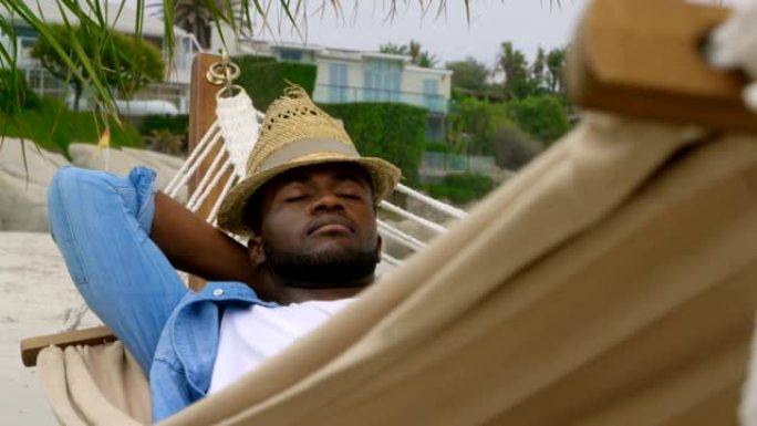 在海滩上的吊床上睡觉的非裔美国人的前视图4k
