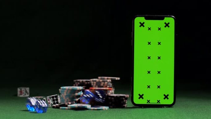 带有绿屏，游戏令牌，在线赌场应用程序，获胜机会的智能手机附近掉落的骰子