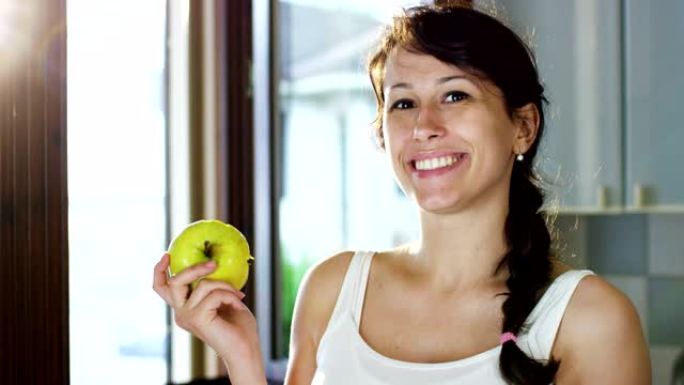 一个夏天的下午，一个年轻的女孩吃了一个新鲜的青苹果来保持健康，尊重他的饮食和微笑