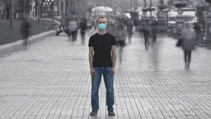那个戴着口罩的年轻人站在拥挤的街道上。时间流逝