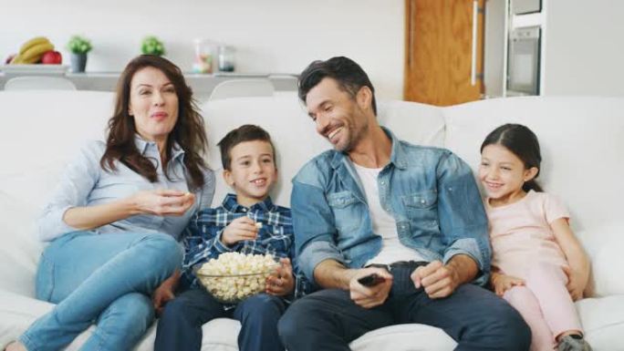 幸福家庭的肖像在客厅的沙发上慢动作看电视。