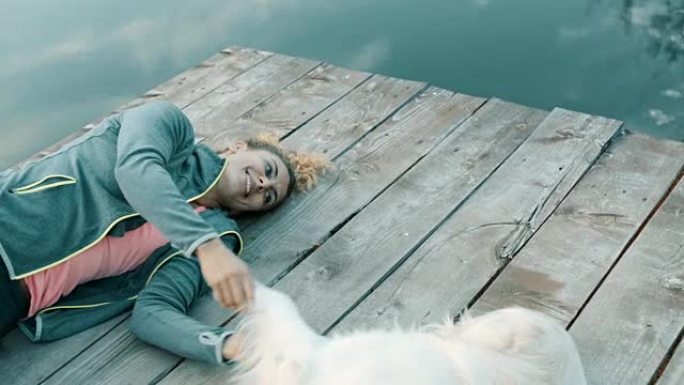 女人和狗躺在湖上的码头上