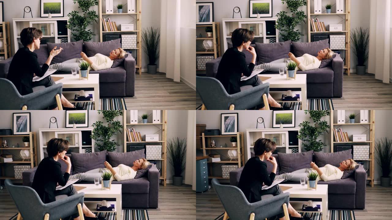 成熟的女士与躺在办公室沙发上的心理学家交谈，分享问题