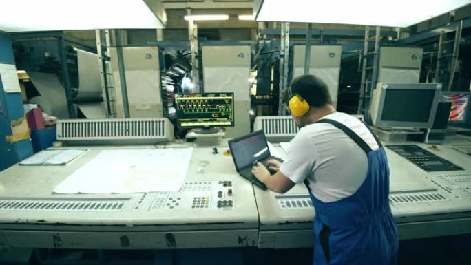 工厂工人用笔记本电脑操作排版设备