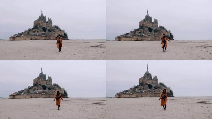 宽镜头美丽快乐的旅游女人在史诗圣米歇尔山城堡慢动作的低潮海沙上缓慢行走