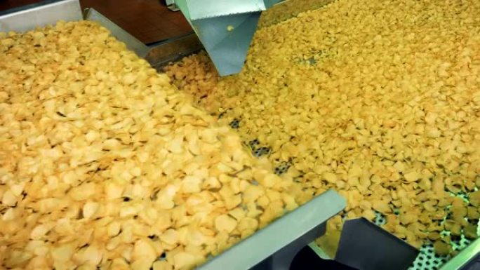从食品设施的工业输送机上掉下来的炸薯片。