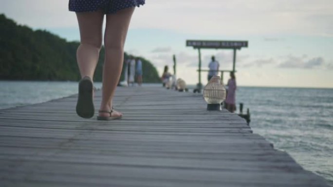 年轻女子在海边的木桥上行走，慢动作