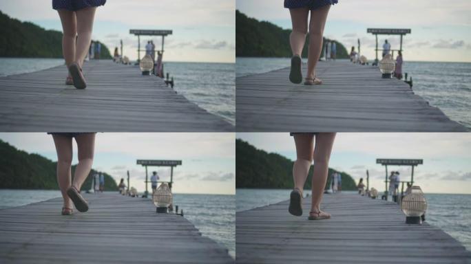 年轻女子在海边的木桥上行走，慢动作