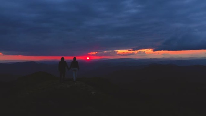 站在山上的男人和女人在日出的背景