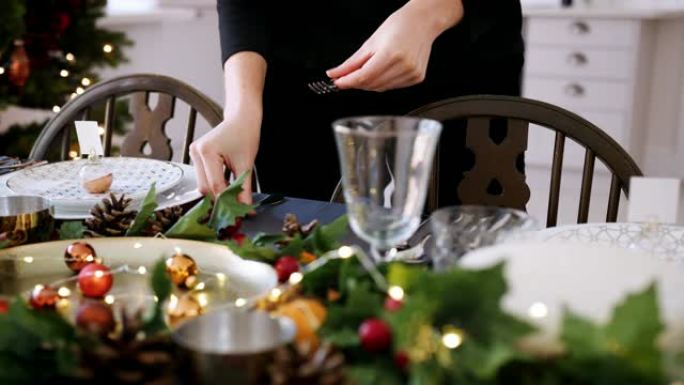 一名妇女的中间部分，在装饰圣诞节晚餐的餐桌上摆放银色餐具，选择性聚焦