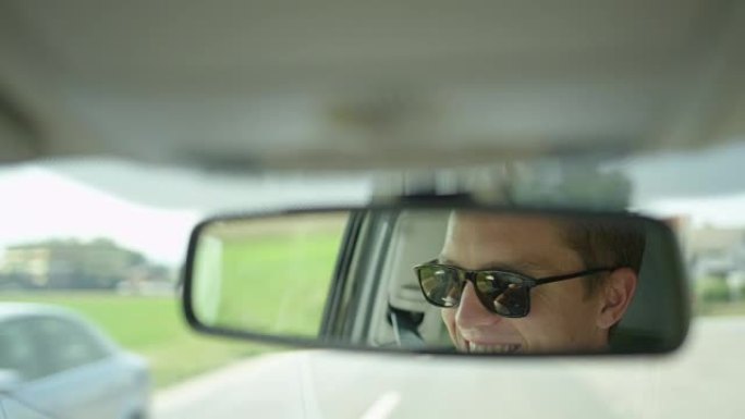 慢动作: 年轻的高加索男性在开车上路时微笑。