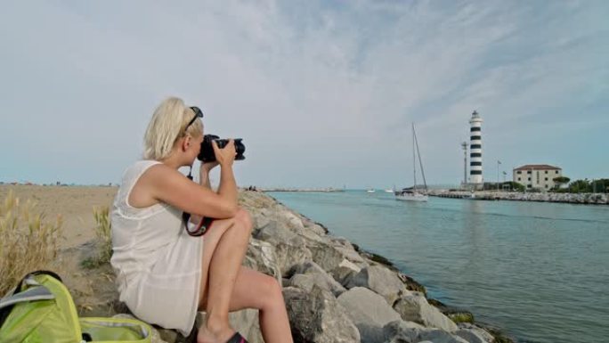 年轻女士在意大利普利亚海滨使用单反相机