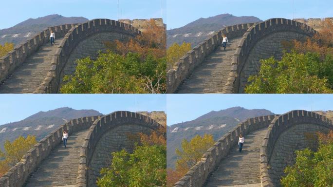 年轻的女摄影师走下长城顶部的古老楼梯