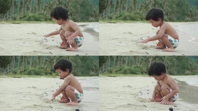 亚洲男婴在海滩上玩沙堡