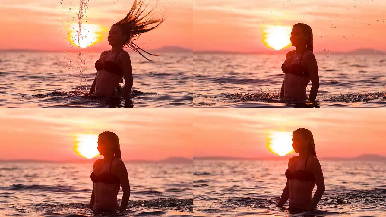 微笑的女人在做头发翻转，日落时泼水