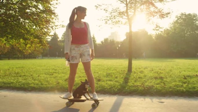 镜头耀斑: 快乐的女孩和可爱的小狗骑着高科技电动长板。