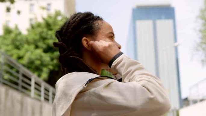 城市4k中戴着耳机的年轻非洲裔美国妇女的侧视图