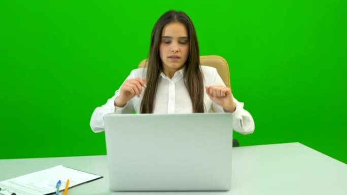 女商人在绿色背景上的台式机上使用笔记本电脑