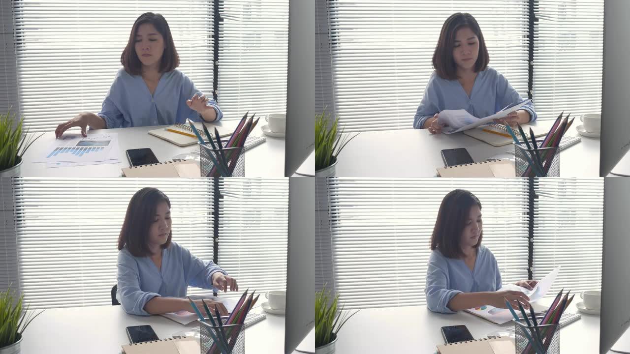 美丽的年轻应变亚洲妇女坐在家里的客厅里在笔记本电脑上工作。在家庭办公室工作的亚洲女商人。