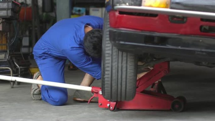 4k: 机械师在汽车维修店使用地板千斤顶汽车。