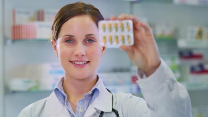 一名年轻女性药剂师顾问在镜头前微笑着展示一包药丸的慢镜头