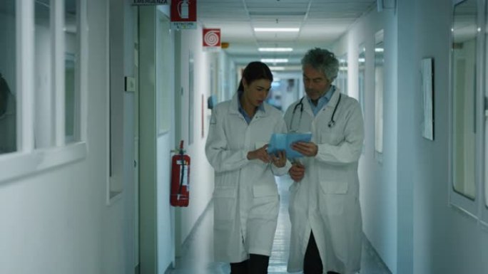 医生和护士在医院病房散步时讨论患者的诊断，以寻求未来治疗的建议。