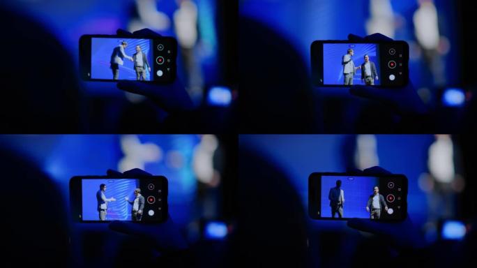 观众使用智能手机记录两名演讲者在商务会议上的讲话。公众使用手机在现场活动中拍摄两名明星主持人的视频。
