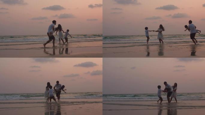 当剪影日落时，爸爸、妈妈和孩子一起放松在海边玩耍。慢动作镜头。
