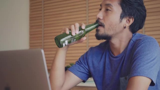 亚洲男子在家与女友在视频会议上喝啤酒。