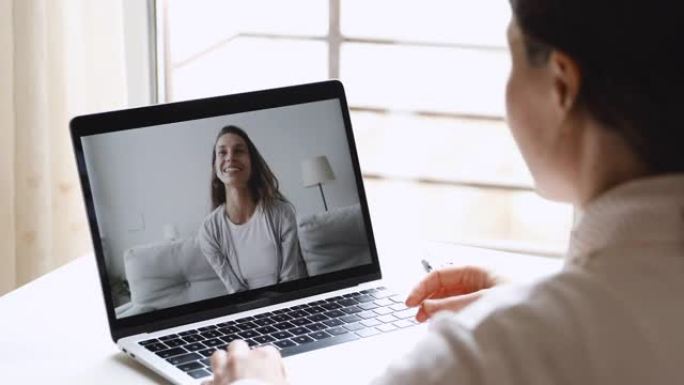 年轻快乐的女人视频在笔记本电脑屏幕上呼叫快乐的朋友