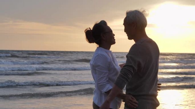 老年夫妇在海边放松。老年假期，假期退休假期概念，快乐的成熟退休夫妇在海滩上享受美丽的日落，老年夫妇在