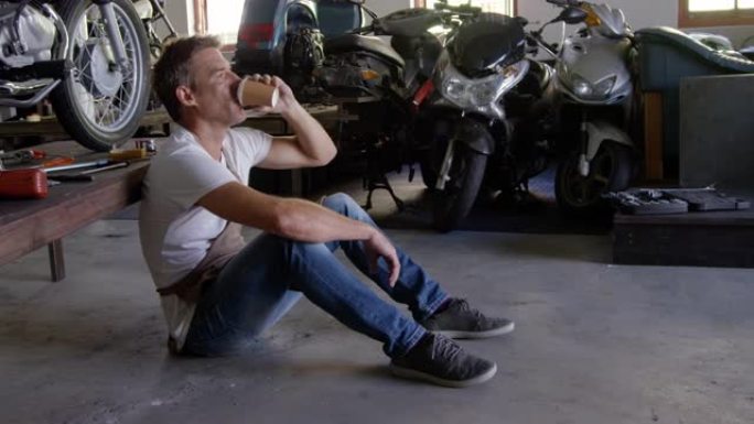 男性机械师在摩托车修理厂4k喝咖啡
