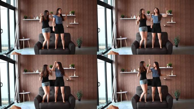 亚洲华裔女性朋友在客厅沙发上跳舞，玩得开心，听音乐，一起享受快乐的时刻