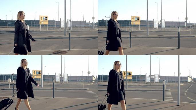 女商人女士带着手提箱在阳光明媚的机场人行道上行走