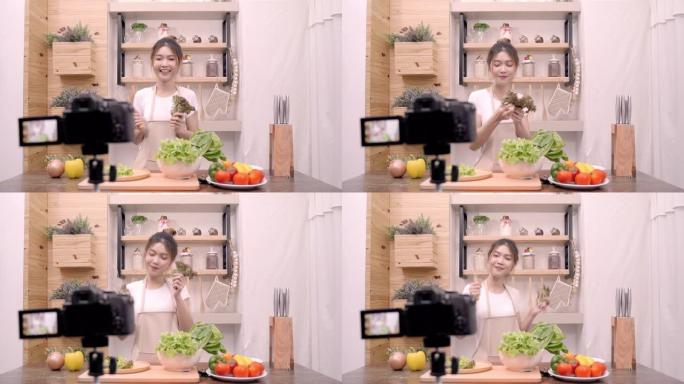 亚洲博主女人在厨房里做vlog沙拉，年轻女性用相机录制跳舞和唱歌感到快乐。生活方式影响者女性健康理念