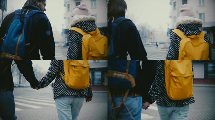在一个白雪皑皑的寒冷的冬日里，穿着休闲服的快乐轻松的年轻浪漫情侣手牵手走在一起。
