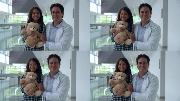 快乐的女孩，医院里的医生抱着一只泰迪熊，然后两人都笑着看着相机