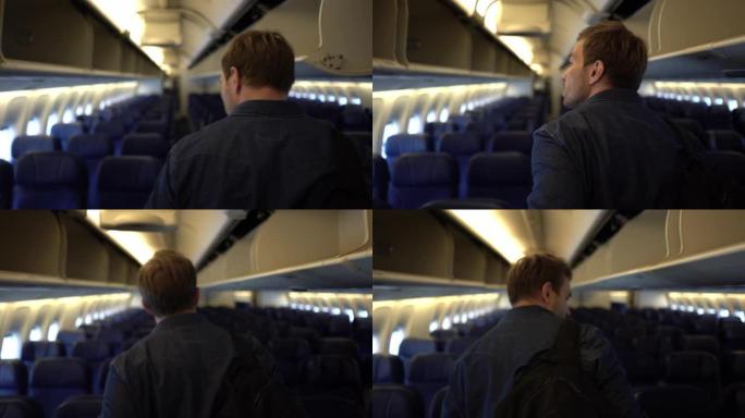 男性乘客沿着飞机过道寻找座位的后视图
