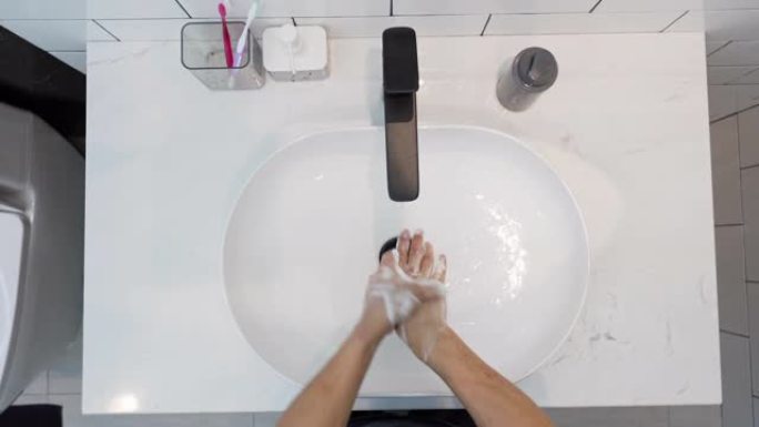 男人用肥皂和水洗手的俯视图