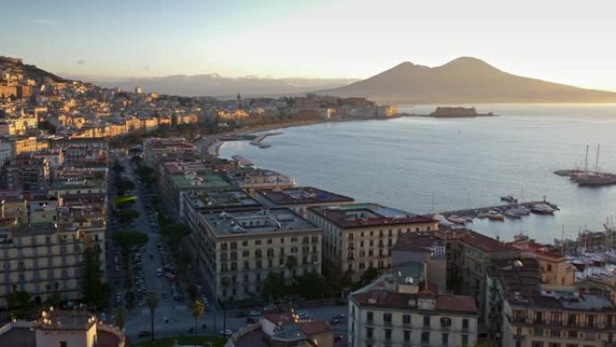 意大利那不勒斯早晨的壮丽全景。汽车驶向城市的街道，船只停靠在海湾。日出时阳光明媚。背景中可以看到维苏