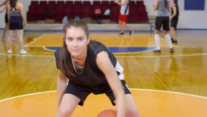 年轻的运动女孩在相机上表演篮球动作
