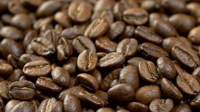 咖啡豆背景。旋转烘焙咖啡豆的特写镜头。4K, UHD