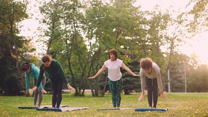 瑜伽学生在周末在公园上课期间在户外练习体式，放松身心。娱乐活动、自然环境和青年观念。