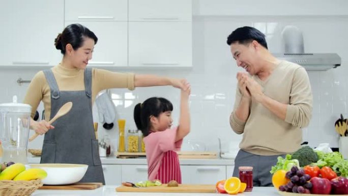 有女儿的年轻家庭在厨房跳舞。泰国家庭在家