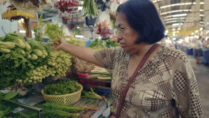 资深亚洲妇女买菜站在农贸市场
