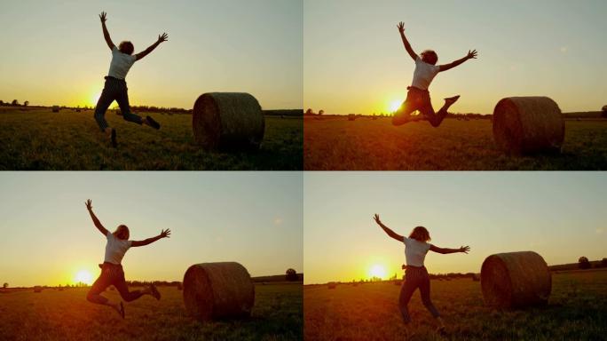 慢动作。女士无忧无虑的女人在日落时带着干草在田园诗般的乡村田野中跳跃