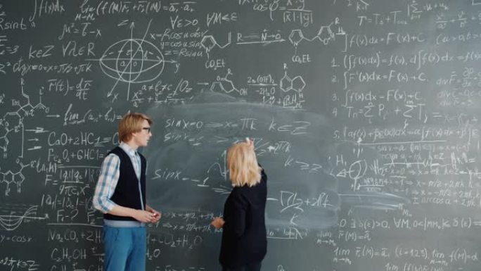 大学教授教授帅哥学生在黑板上写公式
