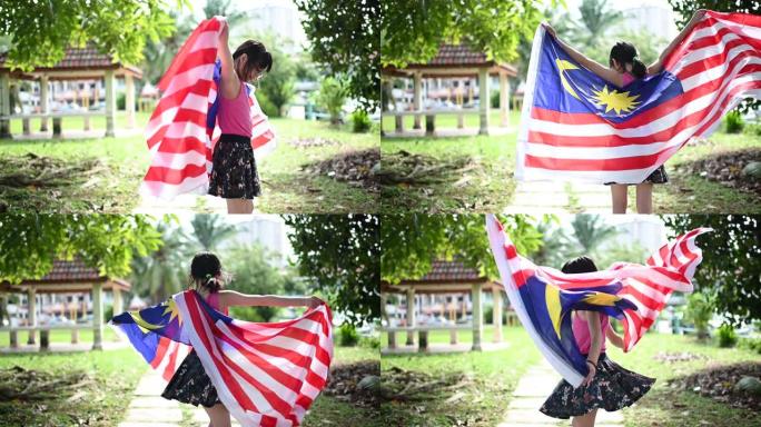 一个裹着马来西亚国旗的亚洲华裔小女孩在公园转身