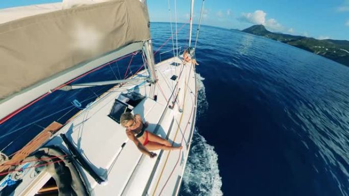 一位女士在帆船上拍摄自己时很有趣。夏季海上假期。