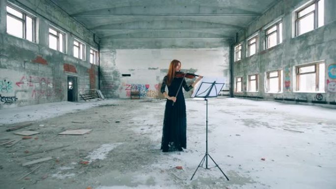 女小提琴手在一栋废弃的建筑里拉小提琴。
